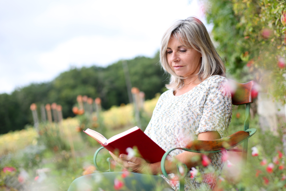 senior reading outside in a field